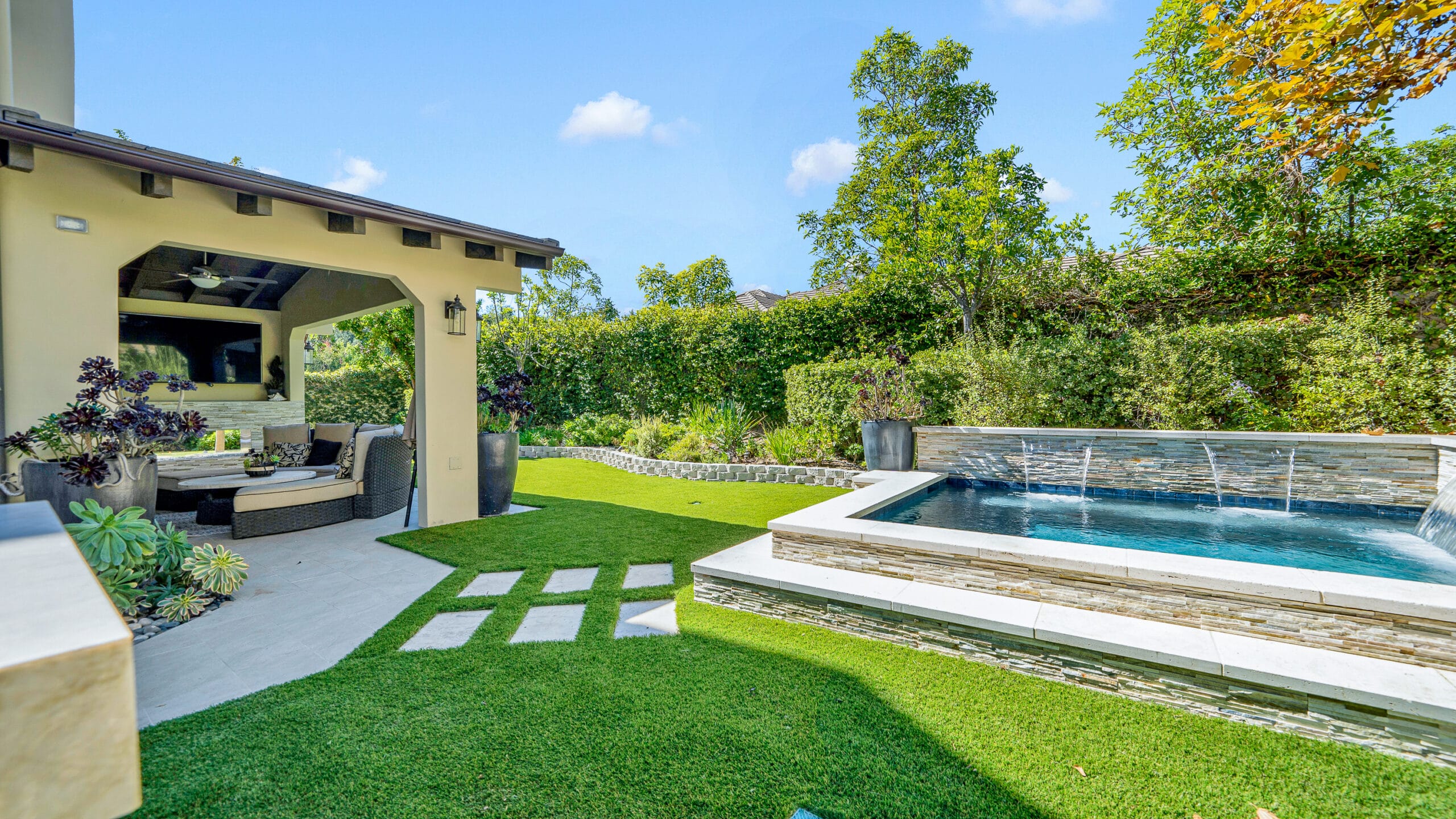 Calabasas backyard pool surround with cascading water feature, paver stepping stones, and artificial turf walkway