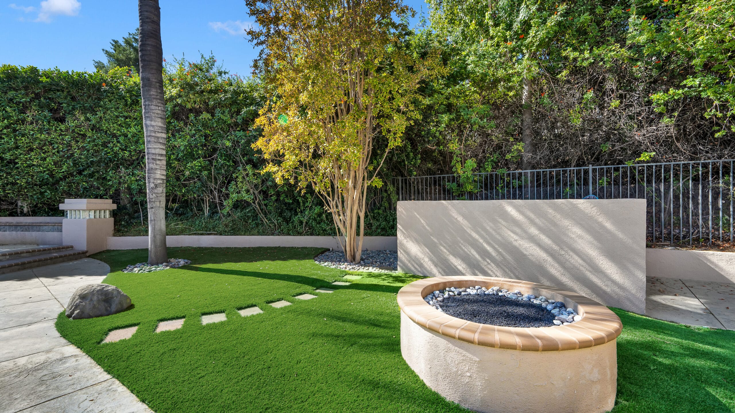 Modern LA backyard install with paver stepping stones across a pristine artificial turf lawn